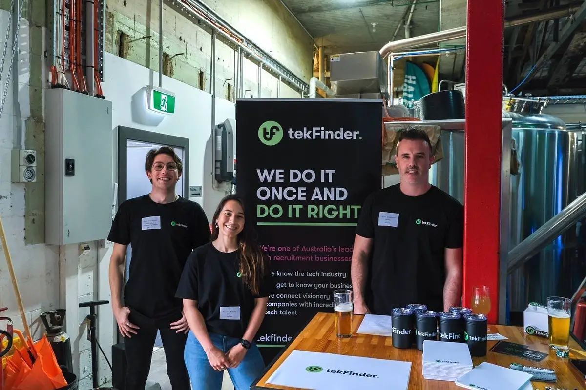 The tekFinder team at its stand at a tech event, with a sign that reads 'We do it once and do it right'