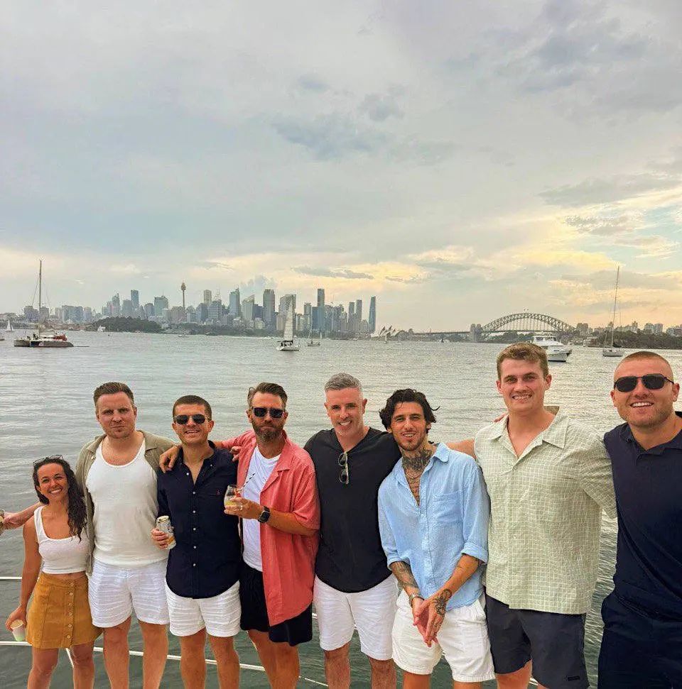 The tekFinder team on a boat on Sydney Harbour, with the city skyline behind
