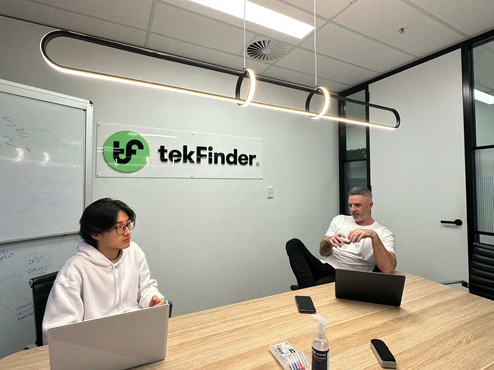 A meeting in the tekFinder office at Martin Place, with the tekFinder logo on the wall